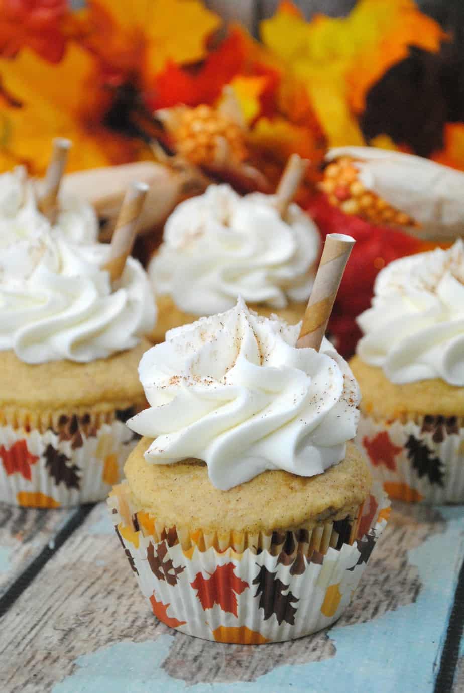 Pumpkin Spice Latte Cupcakes on a wood table with leaves in the background
