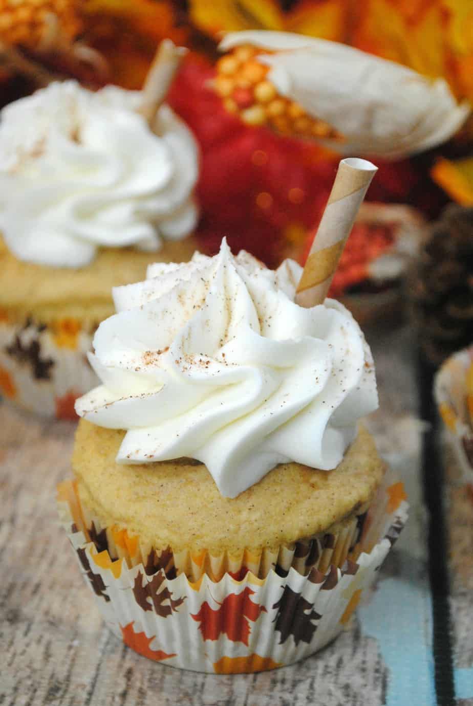 Pumpkin Spice Latte Cupcakes on a wood table with leaves in the background