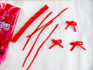 a bag of twizzlers, twizzlers separated into strands and then tied into bows on a white paper