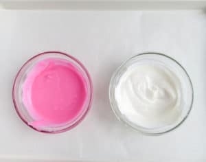 two glass bowls of pink and white melted candy on a white background