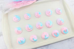 pink and blue meringues on a cookie sheet
