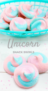 pink and blue meringues in a blue basket and in front of the basket on a white wood table with title text reading Unicorn Snack Swirls