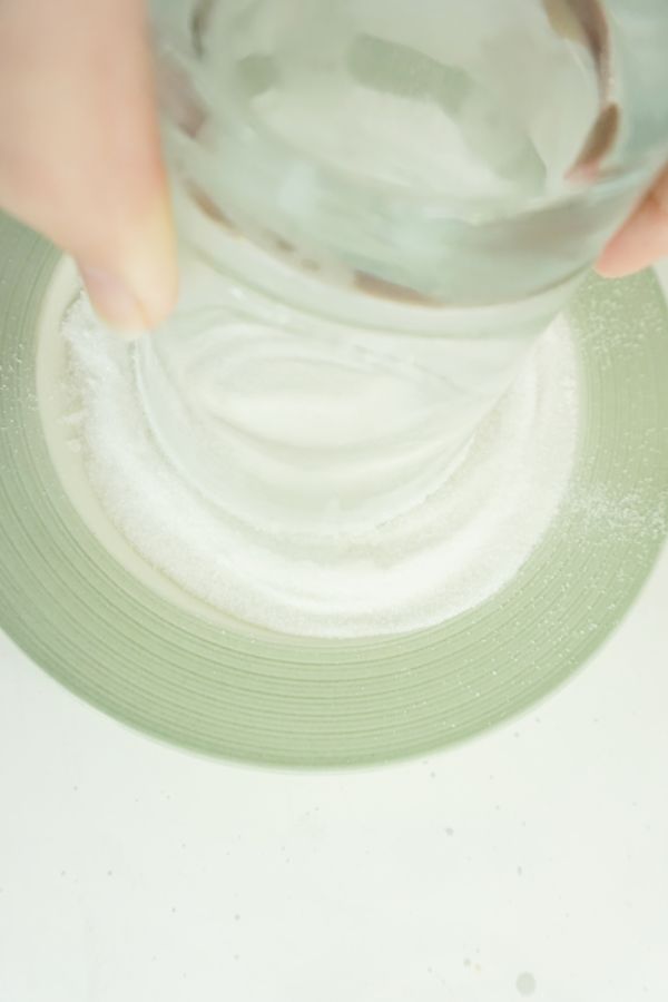 dipping the rim of an upside down glass in a plate of sugar on a white table