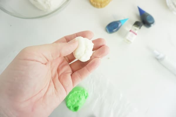 hand holding a ball of white marshmallow fondant to illustrate how to color fondant