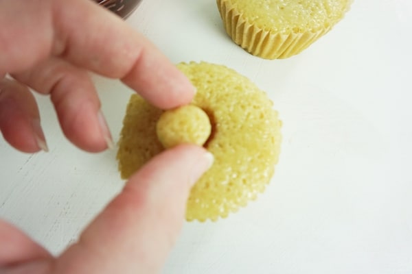 hand putting the top back onto a cupcake well on a white table