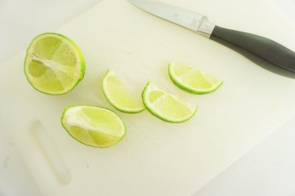 sliced lime on a white cutting board with a knife
