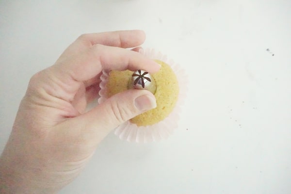decorating tip being pressed into the top of a cupcake to make a well