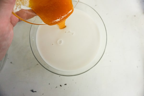 adding caramel to milk in a glass for a caramel flavored frappuccino drink