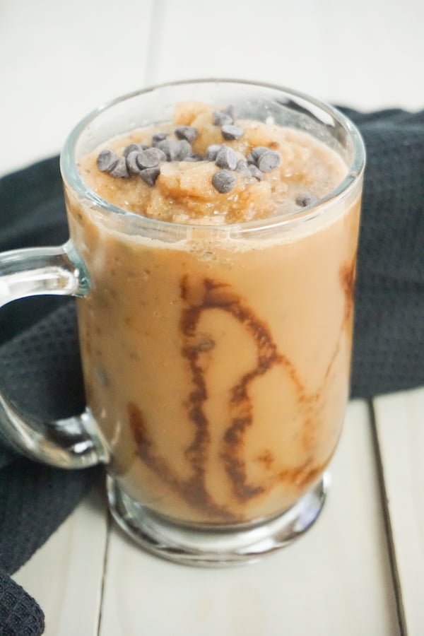 side view of java Chip frappuccino in a glass mug on a grey wood background with a black linen