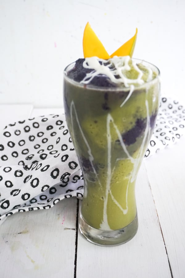 green and purple iced mermaid frappuccino on a white wood background with a black and white linen