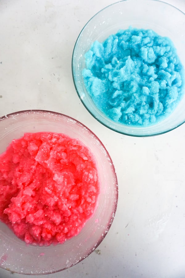 two bowls, one filled with pink ice and one blue ice, the final step in making a unicorn frappuccino. 