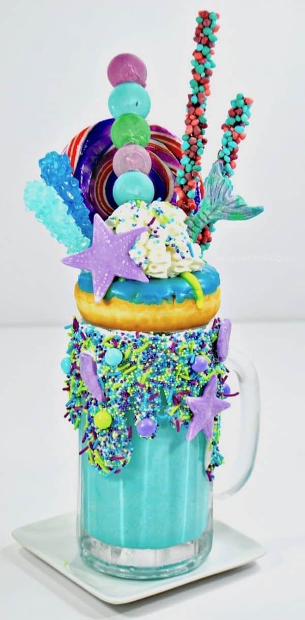 mermaid freakshake by The Soccer Mom Blog in a glass topped with blue and green candy and a blue frosted donut