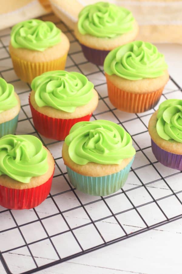 white cupcakes topped with green frosting on a wire rack