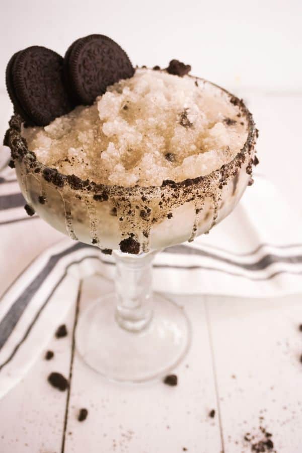 Cookies and Cream Margarita in a glass next to a black and white cloth on a white wood table 