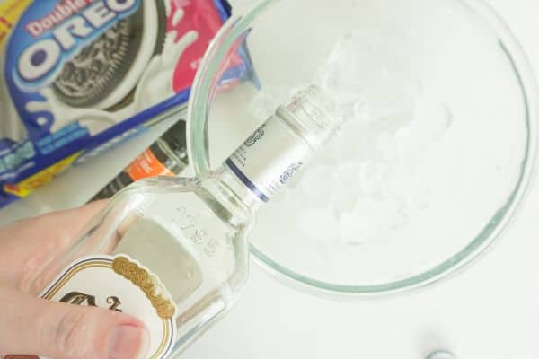 tequila being poured into a bowl of ice next to oreos and triple sec on a white background