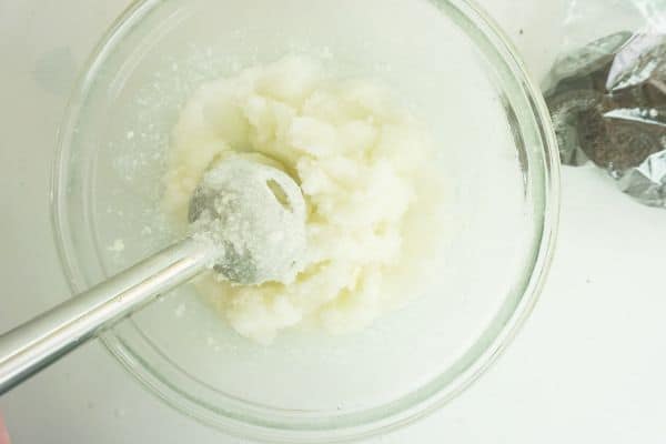 an immersion blender mixing the ingredients for a Cookies and Cream Margarita, next to a bag of oreos on a white background