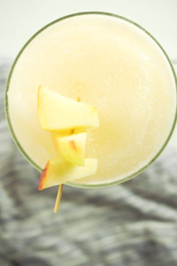 overhead view of Caramel Apple Margarita in a glass with apple slices on a toothpick on the rim