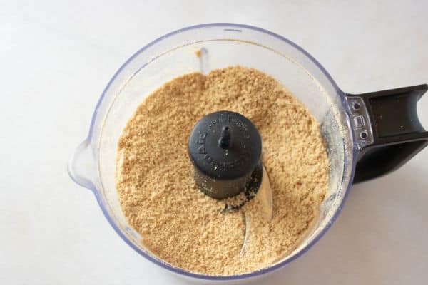 graham cracker crumbs in a food processor on a white counter