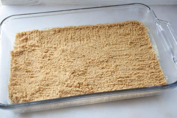 graham cracker crumbs in a glass baking dish on a white counter