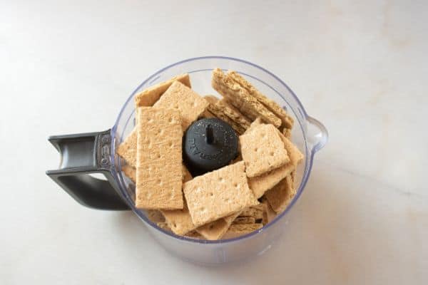 graham crackers in a food processor on a white counter