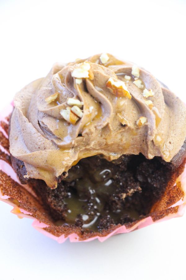 closeup of a turtle cupcake with a piece missing so you can see the caramel filling inside