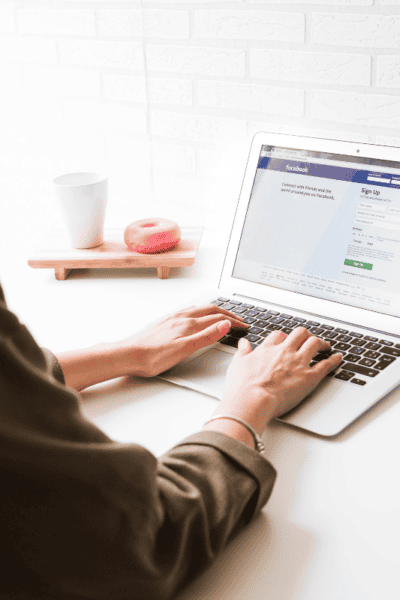 An image of a woman on a laptop with the Facebook login page on it.