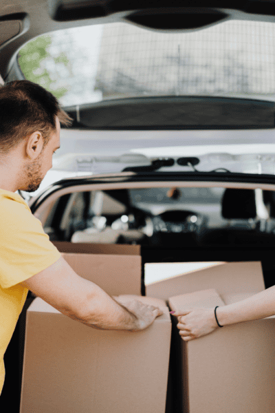 A man and a woman packing boxes in the back of a car.