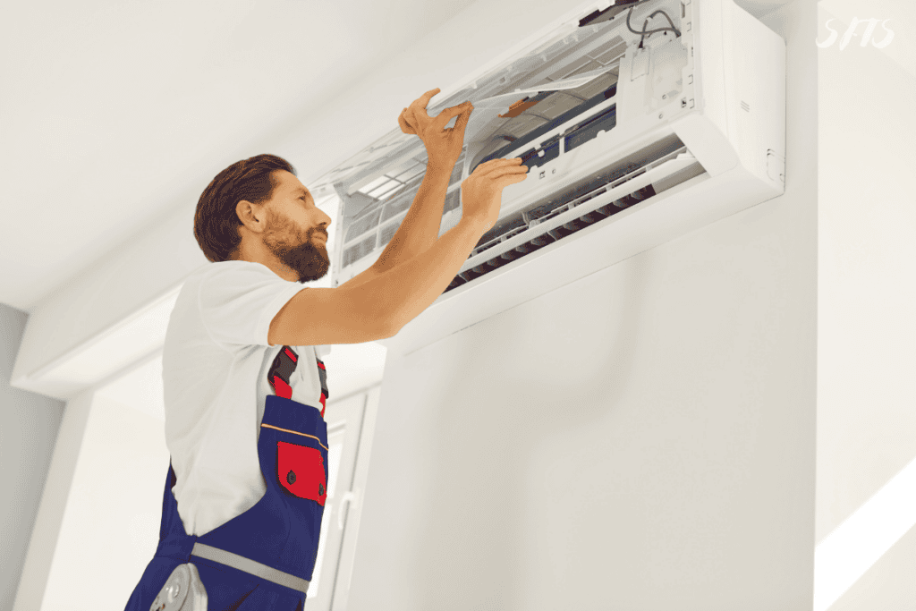An image of a man cleaning an AC unit.