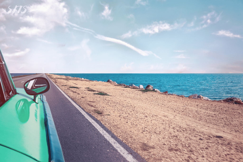 An image of a car driving through the coastline.